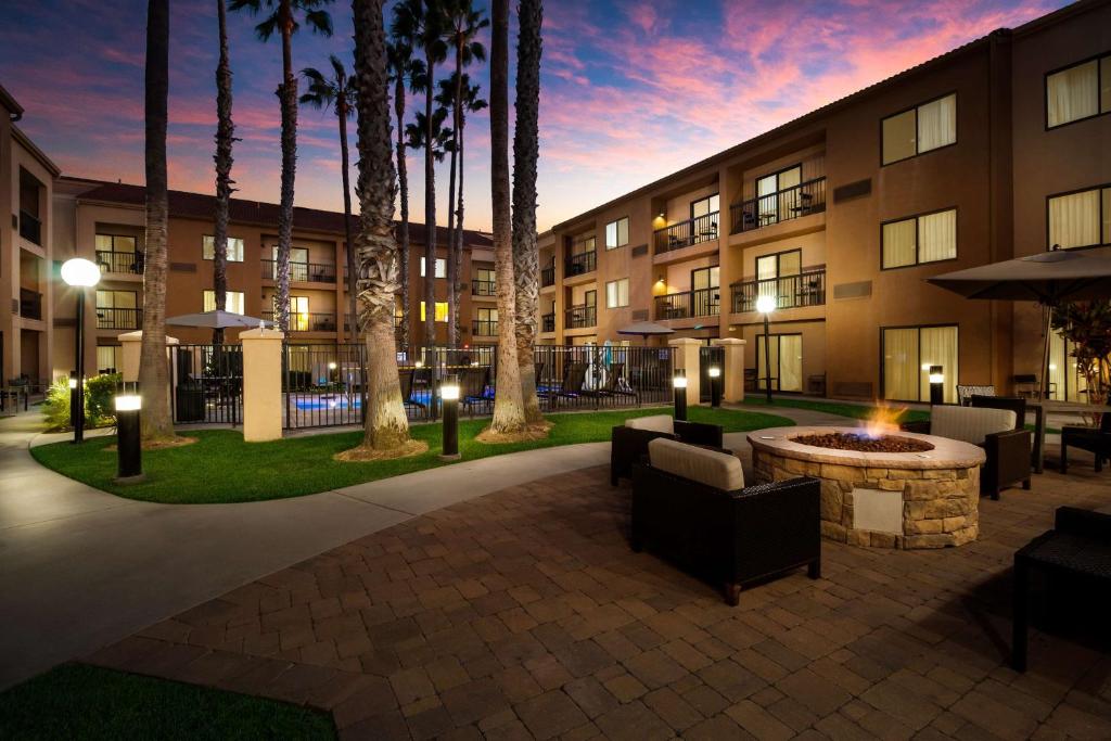 Un patio de hotel con fogata y palmeras. en Sonesta Select Huntington Beach Fountain Valley, en Huntington Beach