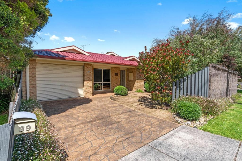 a brick house with a fence and a driveway at Serenity Now Inverloch in Inverloch
