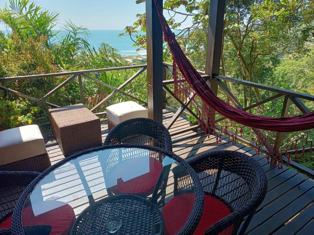 a table and chairs on a porch with a hammock at La Roca Studio 7 in Praia do Rosa