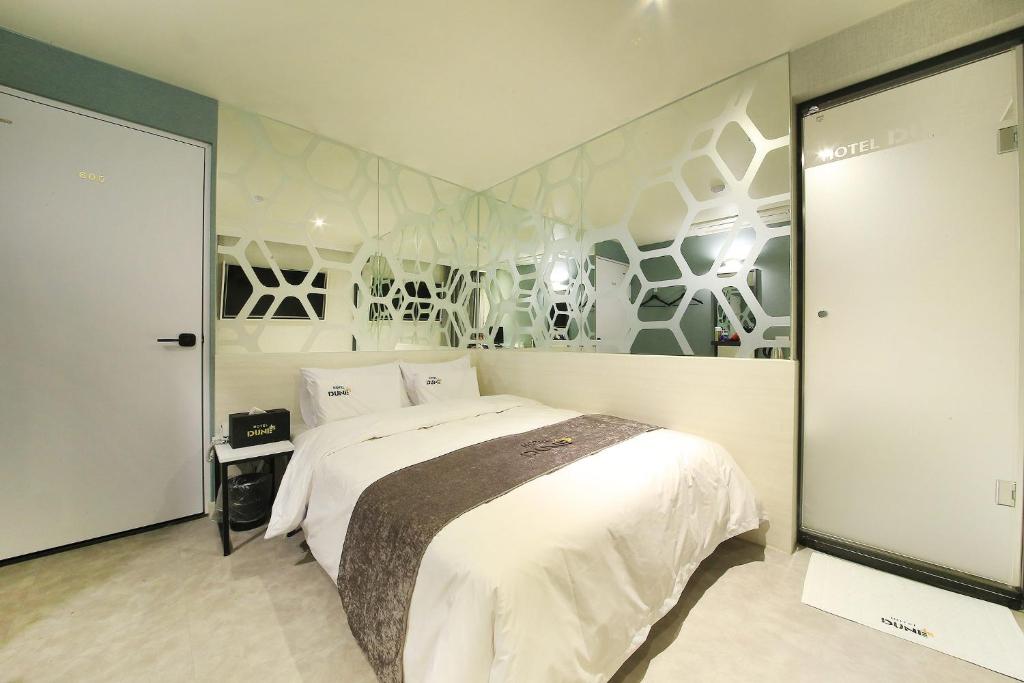 スウォンにあるDUNE45の白い大型ベッドと壁画が備わるベッドルーム1室が備わります。