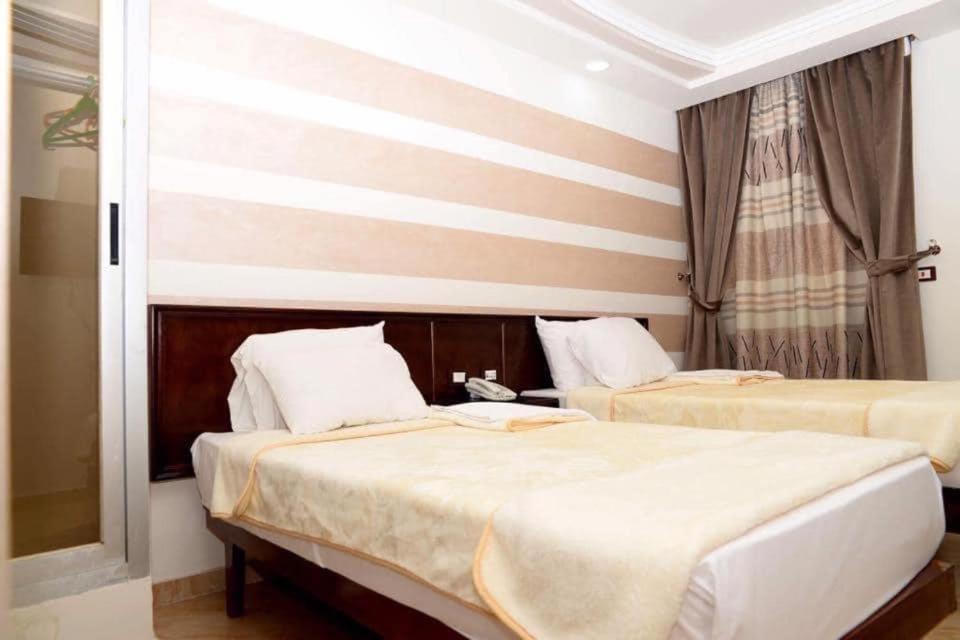 a bedroom with two beds and a window at Salvatore Room With Breakfast-Behind Asyut Train Station in Asyut