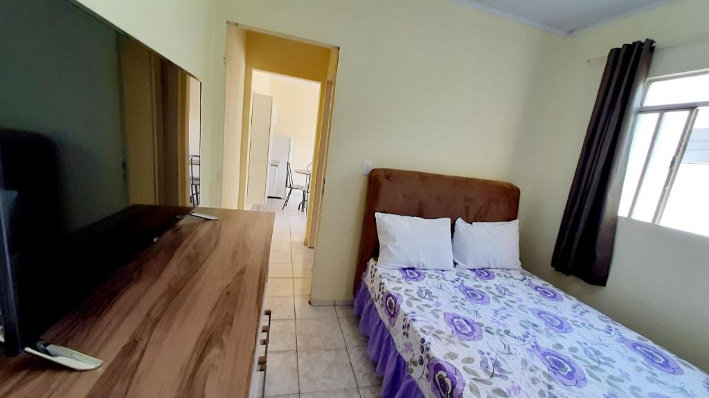 a bedroom with a bed and a flat screen tv at hospedagensjaguariaiva in Jaguariaíva