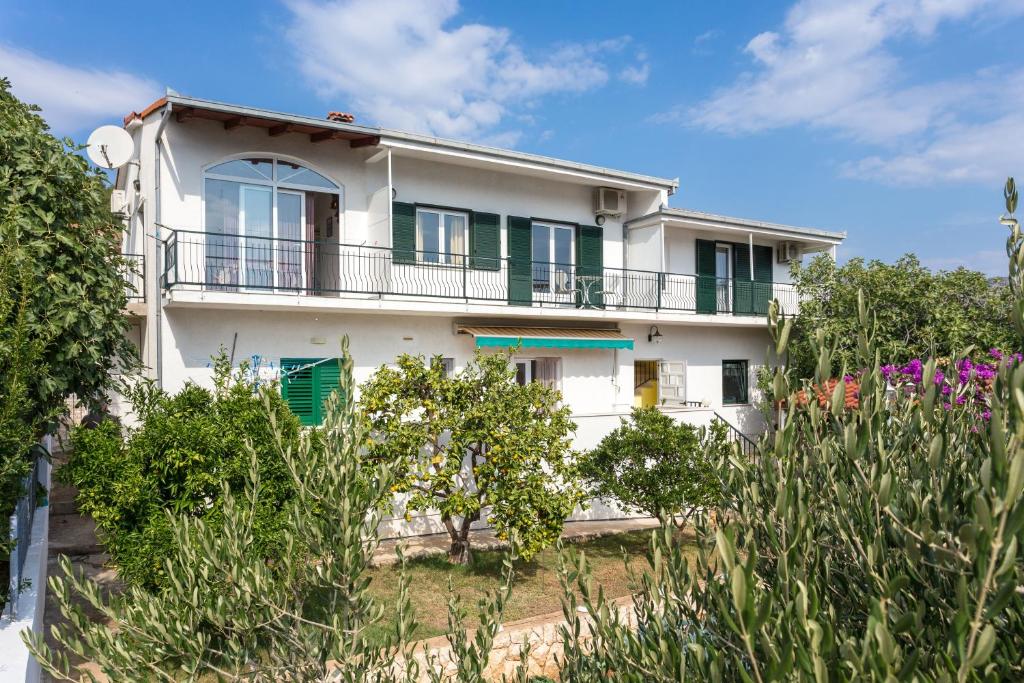 een wit huis met groene ramen en bomen bij Apartments by the sea Poljica, Trogir - 16999 in Marina