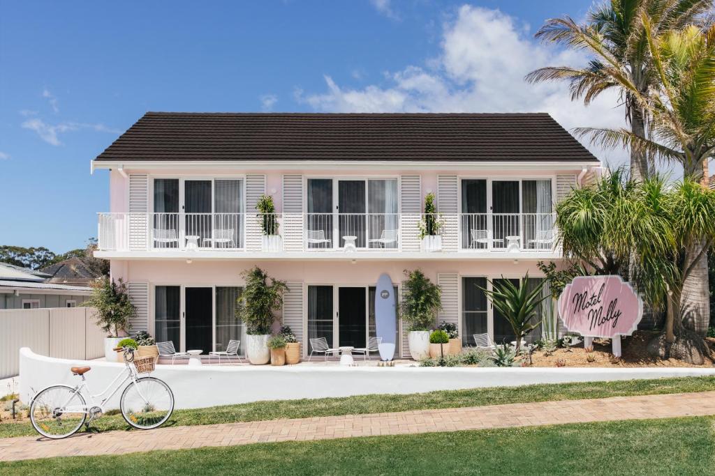 una bicicleta estacionada frente a una casa rosa en Motel Molly - Boutique Hotel Mollymook, en Mollymook