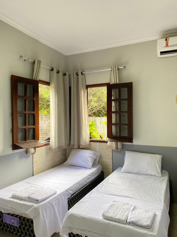 zwei Betten in einem Zimmer mit zwei Fenstern in der Unterkunft Barreirinhas - Casa no Condomínio dos Jipeiros in Barreirinhas