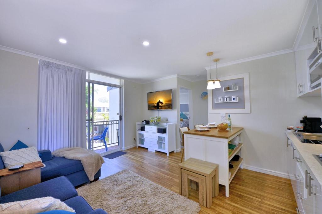 a living room with a blue couch and a kitchen at 7 Heaven in Mandurah