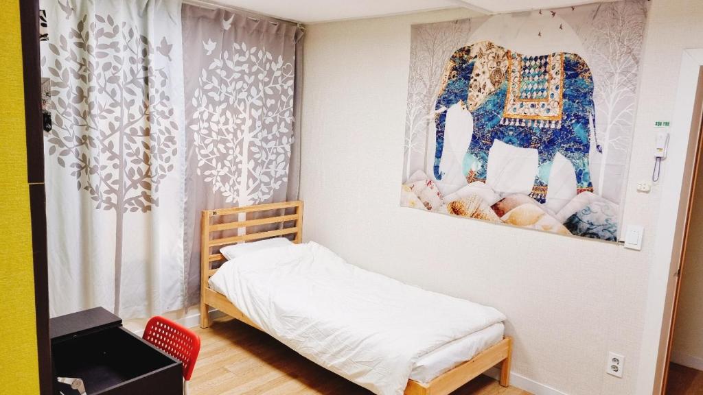 a small bedroom with a bed and a painting on the wall at Agit Guesthouse in Seoul