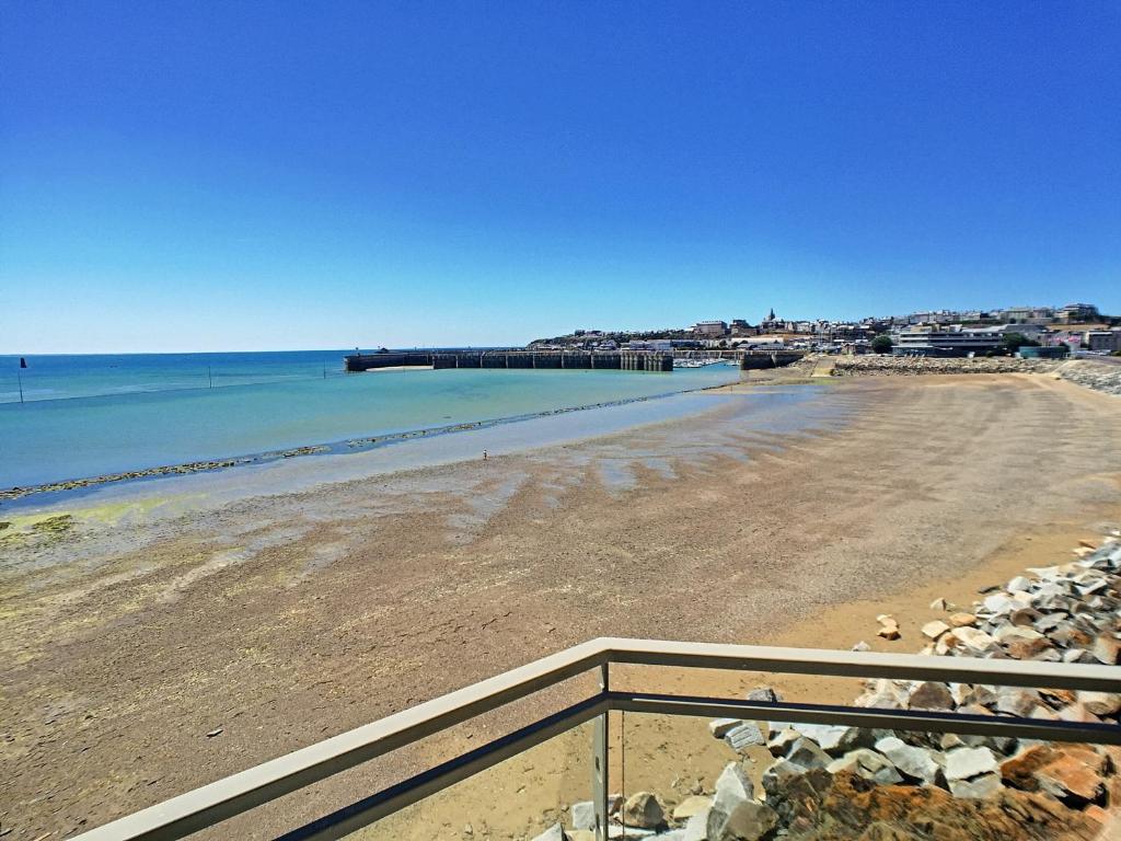 a view of a beach with the ocean and a pier at Bel appartement en front de mer avec balcon, parking et équipements modernes - FR-1-361-327 in Granville