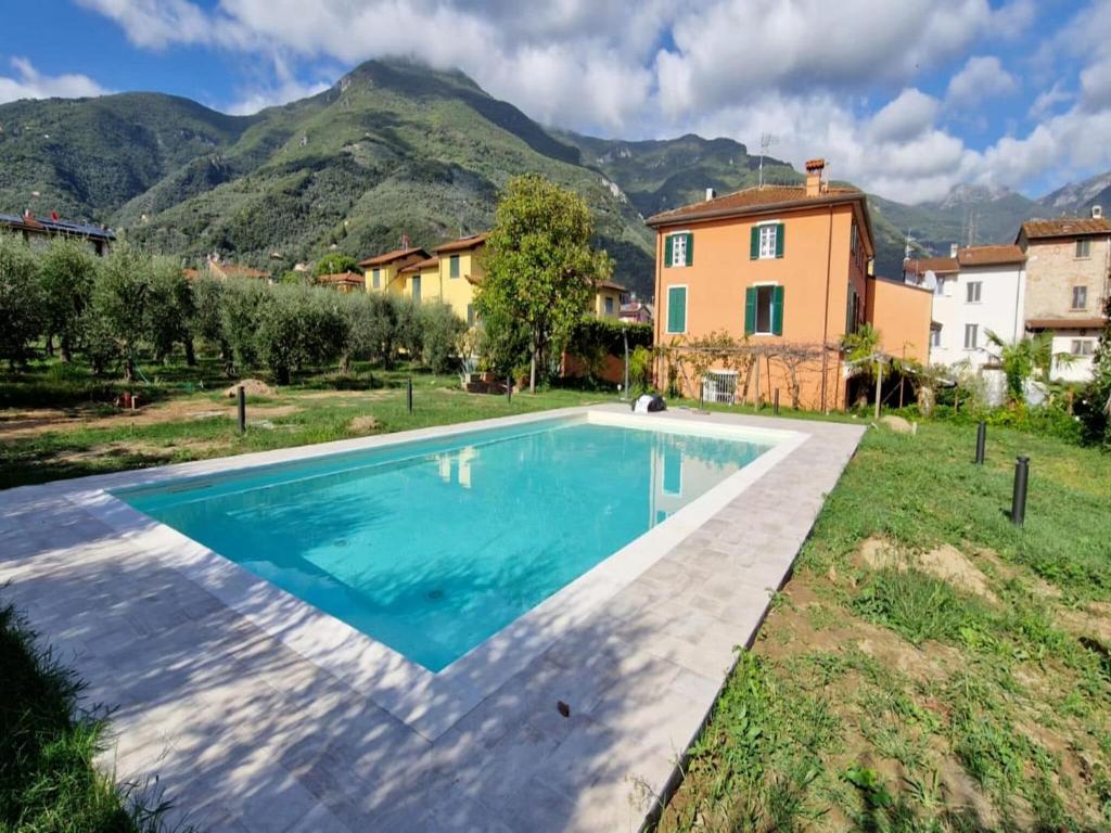 uma piscina com casa e montanhas ao fundo em Belvilla by OYO Casa Teresa em Camaiore