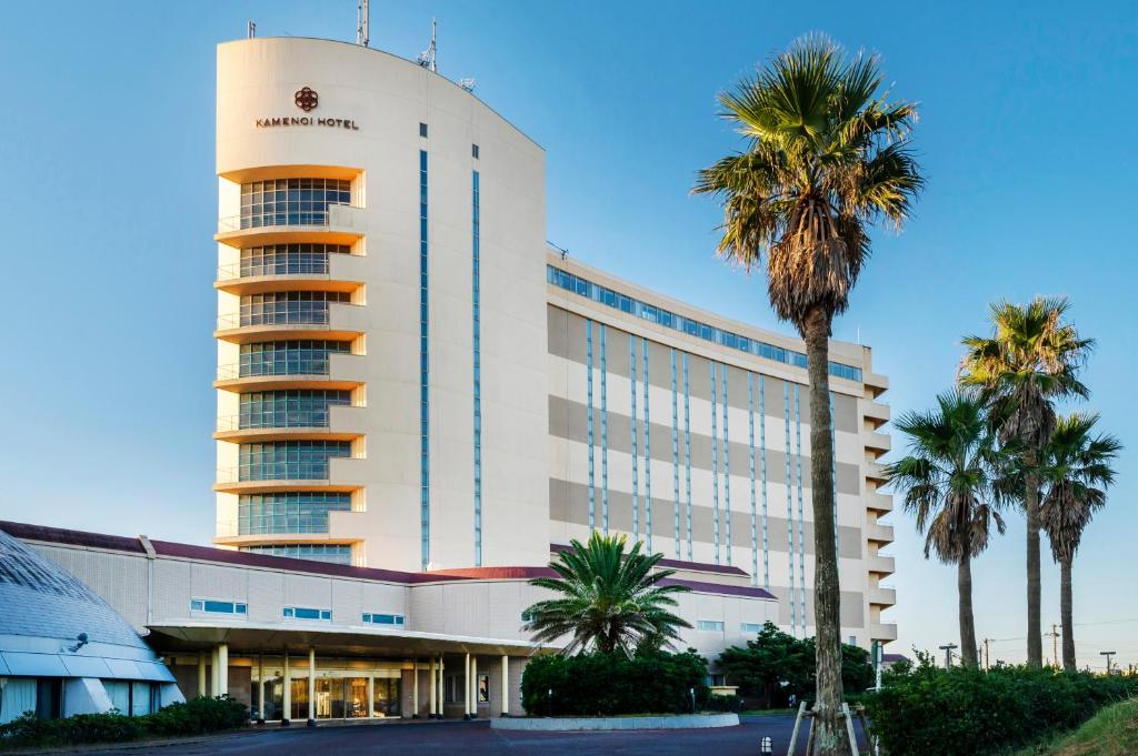 a large building with palm trees in front of it at KAMENOI HOTEL Kujukuri in Asahi
