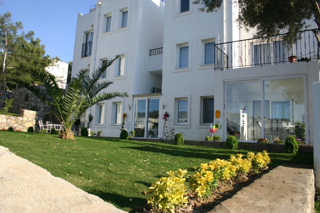 un edificio blanco con césped delante en Rose Residence, en Bodrum City