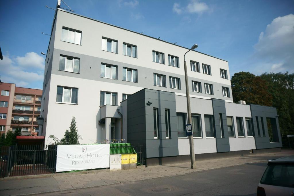 Biały budynek z światłem ulicznym przed nim w obiekcie Hotel Vega w mieście Lębork