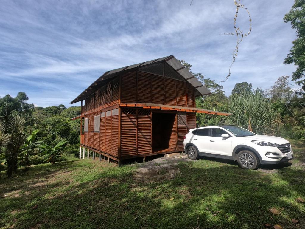 une petite maison en bois avec une voiture garée à côté dans l'établissement Eco Guest House - Sarapiquí 1, à Sarapiquí