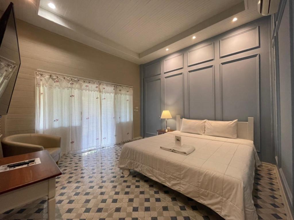 1 dormitorio con 1 cama blanca grande y escritorio en Aob-Oun Homestay, en Pak Chong