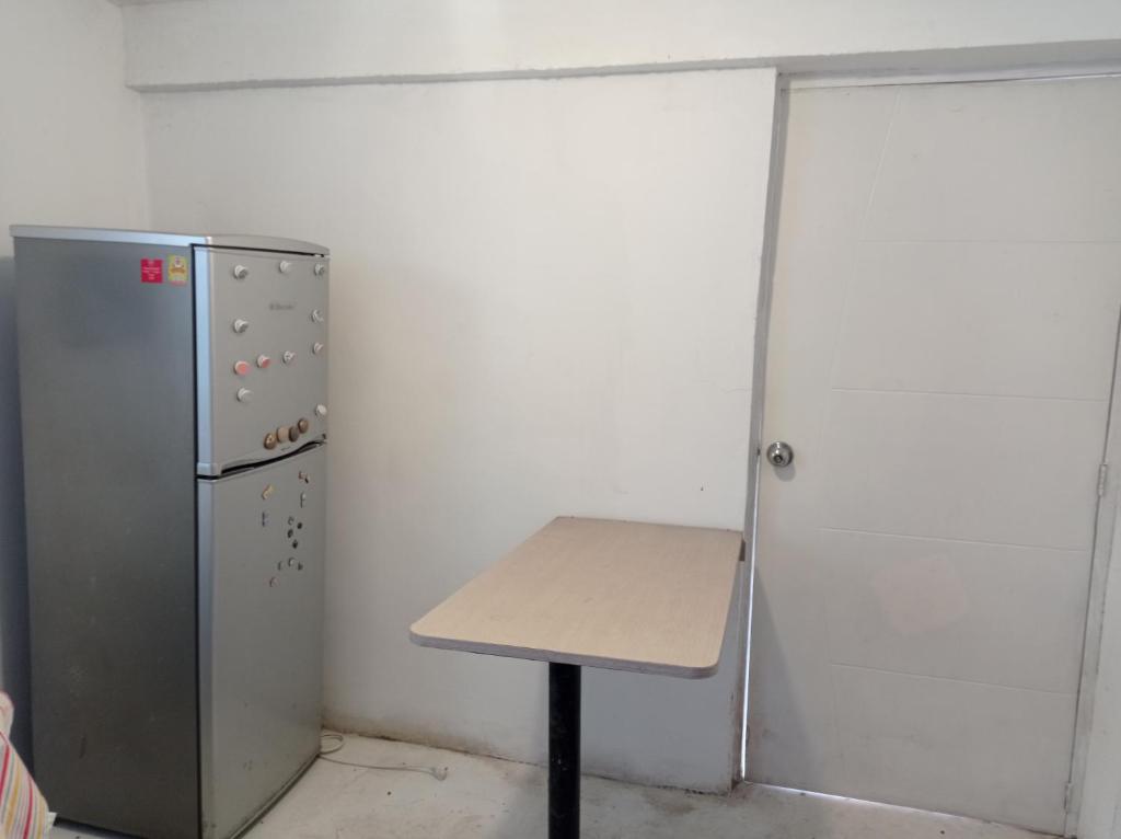 einen Tisch in einem Zimmer neben einem Kühlschrank in der Unterkunft FER'S HOUSE in Lima