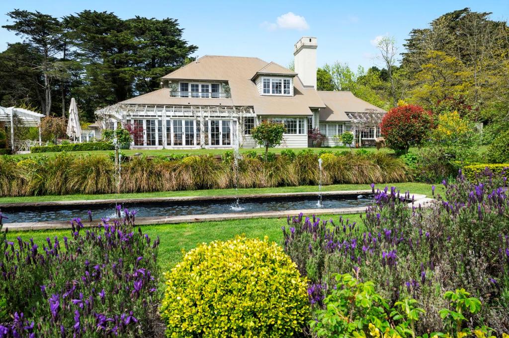 uma casa com jardim e flores no primeiro plano em Parklands Country Gardens & Lodges Blue Mountains em Blackheath