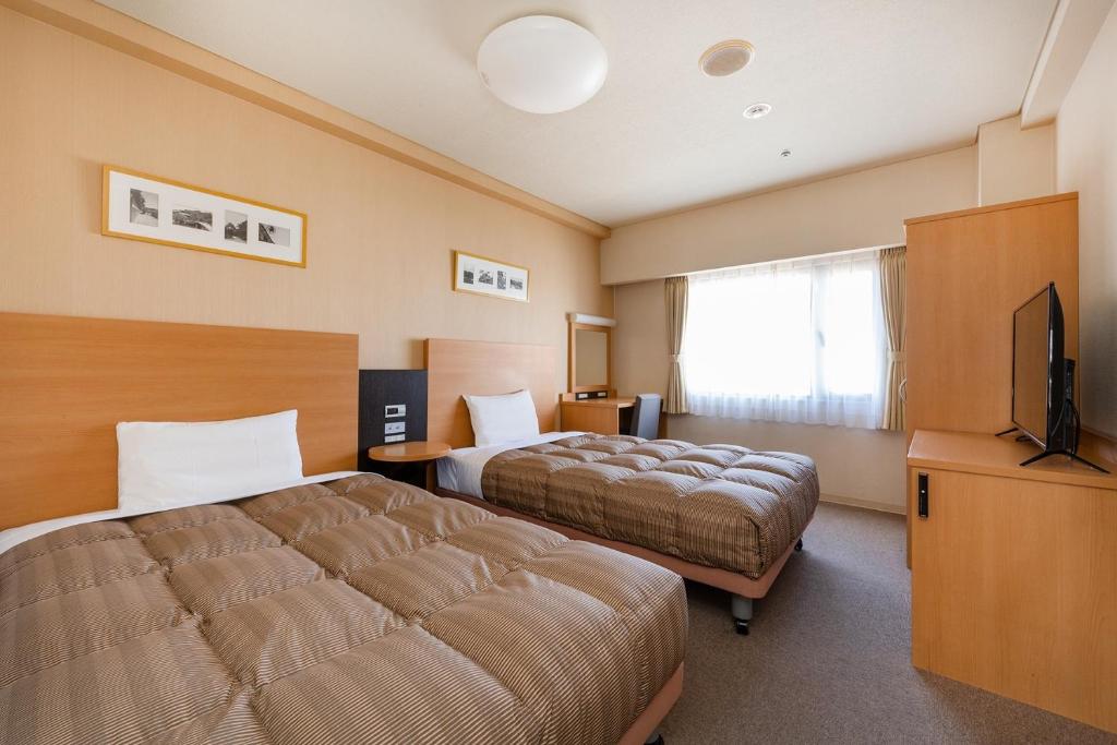 ein Hotelzimmer mit 2 Betten und einem Flachbild-TV in der Unterkunft The OneFive Okayama - Vacation STAY 41848v in Okayama