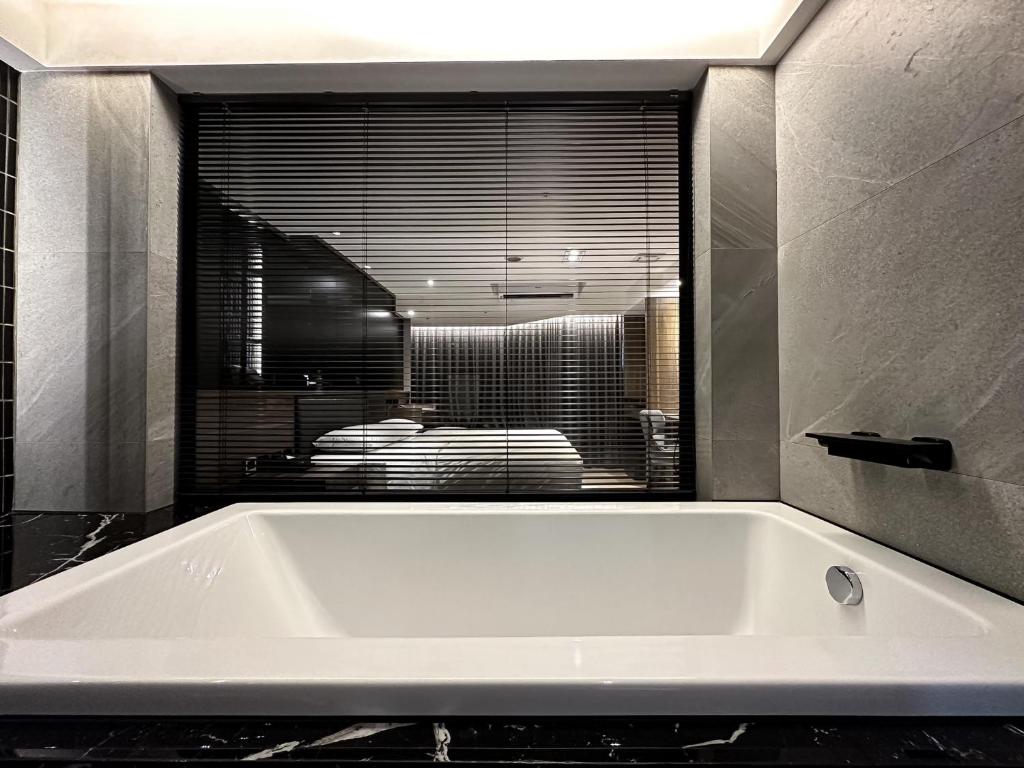 a white bath tub in a bathroom with a window at Autumn Willow Hotel in Taichung