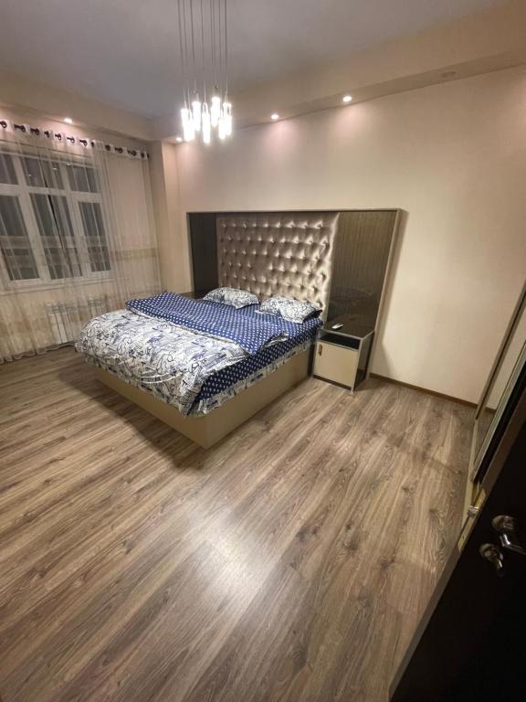 1 dormitorio con 1 cama y suelo de madera en Flamingo en Dushanbe