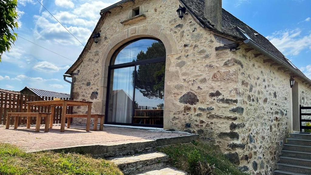 un bâtiment en pierre avec une fenêtre et une table en bois dans l'établissement Maison charmante à Maleville avec jardin privé et parking.B, à Maleville
