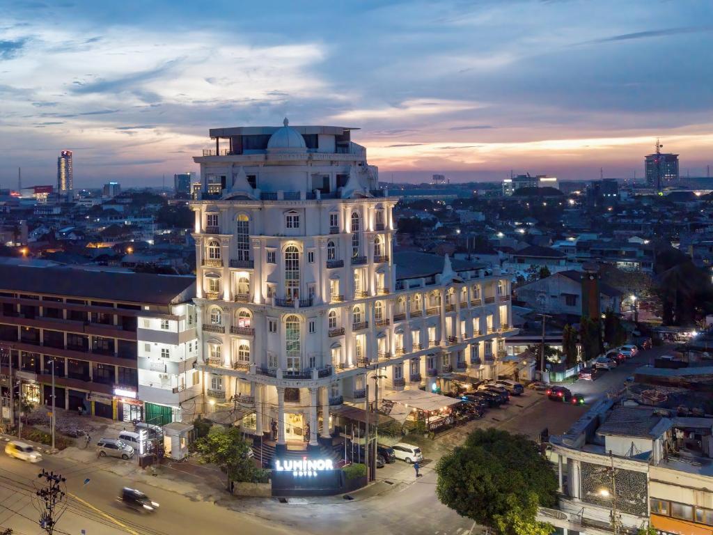 um grande edifício branco numa cidade à noite em Luminor Hotel Palembang by WH em Palimbão
