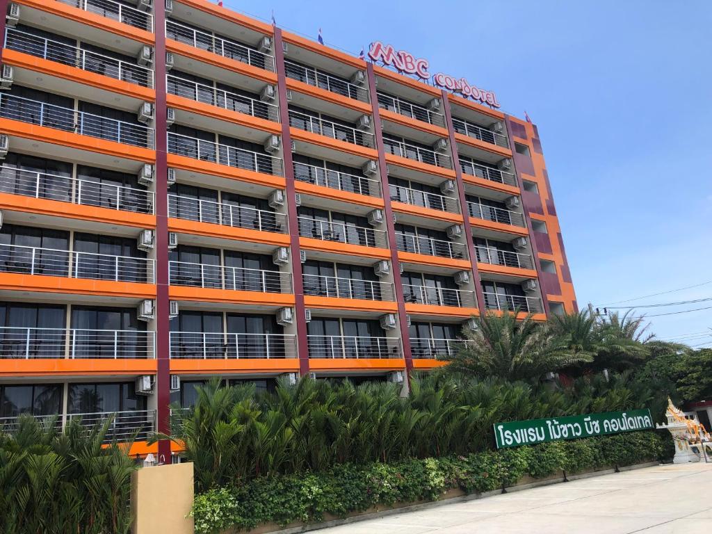 an orange building with palm trees in front of it at Mai Khao Beach Apartments -MBC- in Ban Bo Sai Klang