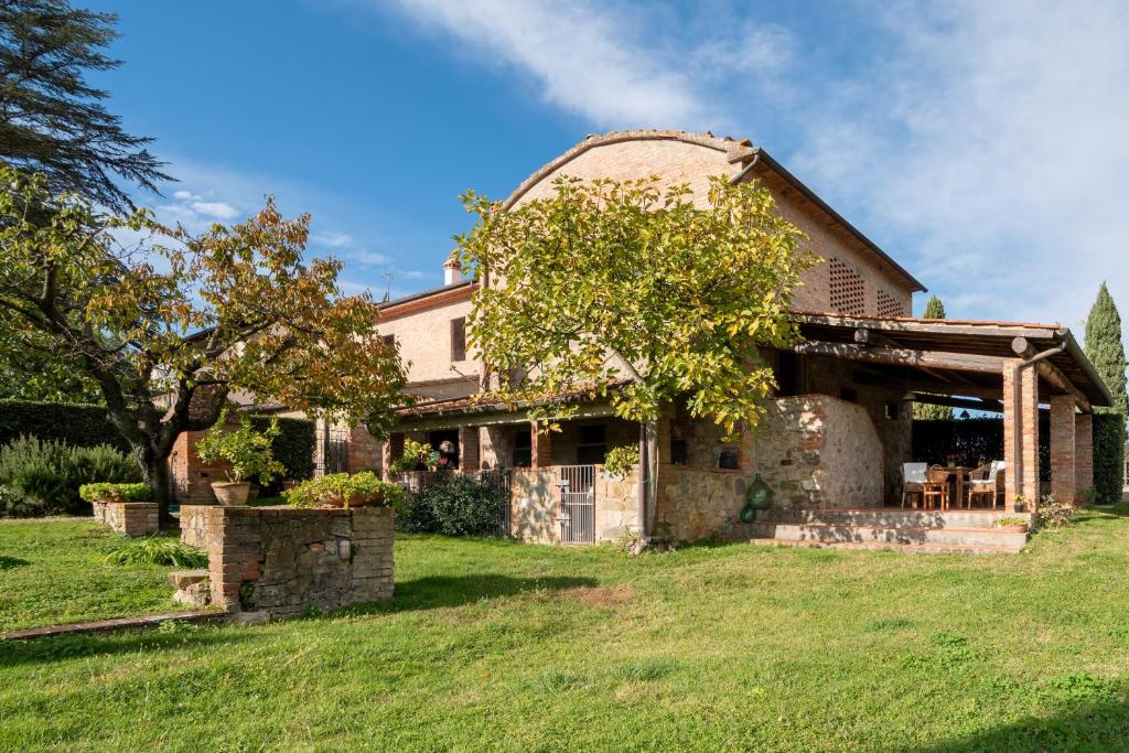 Villa Il Fienile Il Sole Verde في Bucine: منزل من الطوب القديم في ساحة مع شجرة