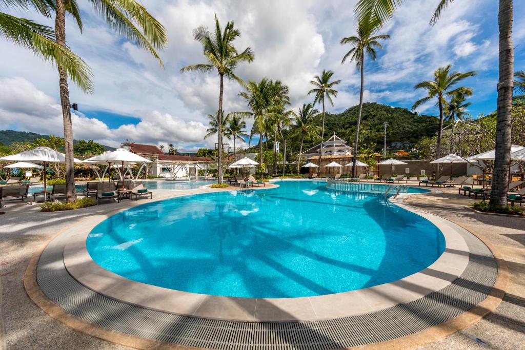 a large pool with palm trees and umbrellas at Outrigger Koh Samui Beach Resort - SHA Extra Plus in Lamai