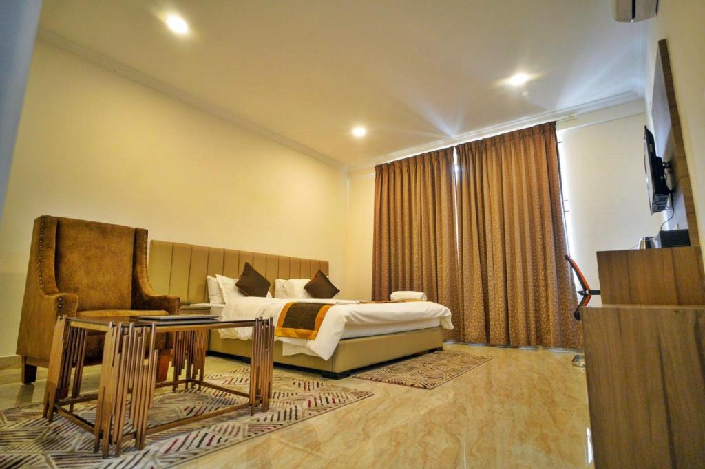 Hotel Sterling Inn في بانغالور: غرفة نوم بسرير وطاولة واريكة