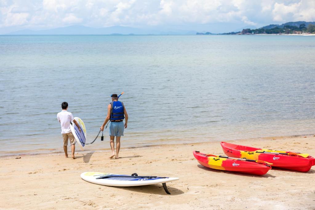 two men standing on the beach with their surfboards at Outrigger Koh Samui Beach Resort - SHA Extra Plus in Lamai
