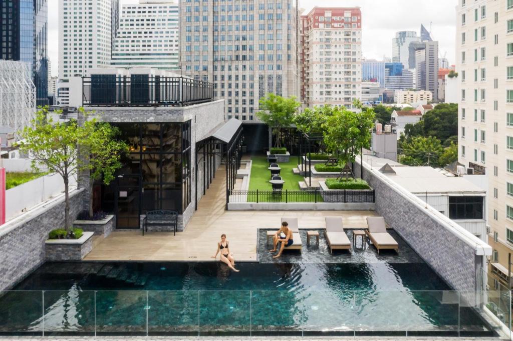 two people sitting in a pool on top of a building at Montraj Coach Sukhumvit Bangkok in Bangkok