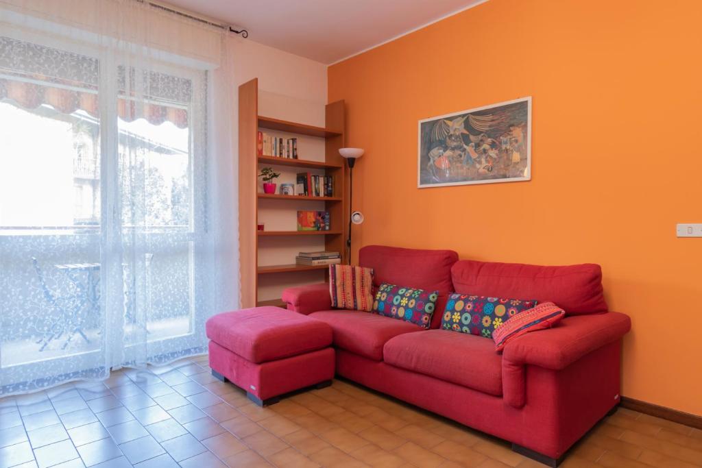 un sofá rojo en una sala de estar con una pared de color naranja en [Buccinasco apartment] Mascherpa en Buccinasco