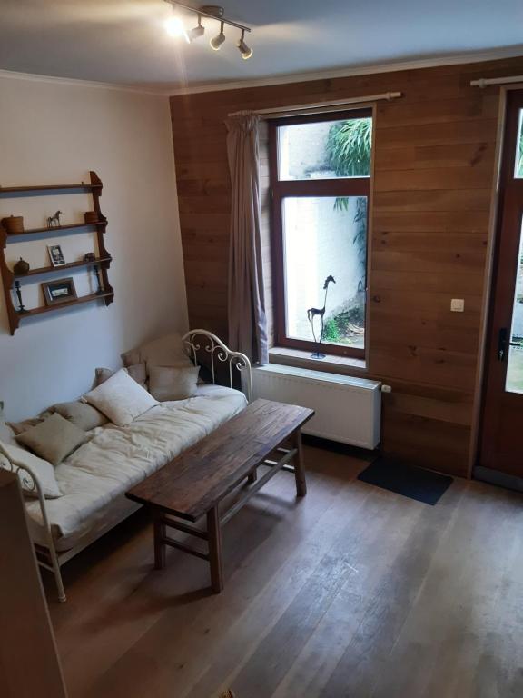 uma sala de estar com um sofá, uma mesa e uma janela em Maison cosy au centre de Nivelles em Nivelles