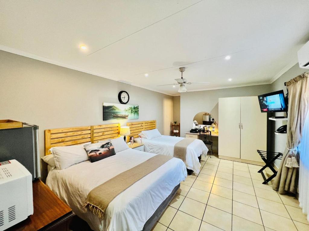 a hotel room with two beds and a television at Echo Mountain Inn in Thabazimbi