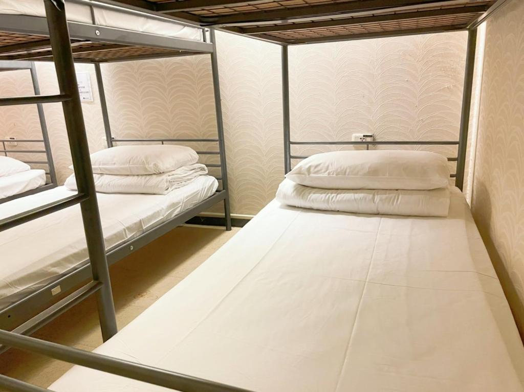 高雄市にあるシングルイン 高雄林森のドミトリールーム 白い枕、二段ベッド2台