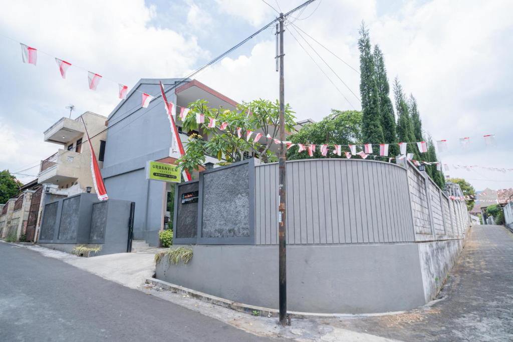 a house with a fence and flags on a street at Urbanview Hotel Bubusini Batu by RedDoorz in Batu
