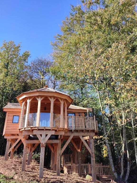 une grande cabane dans les arbres avec une terrasse dans l'établissement Le Domaine des Roches' L, à Gommené