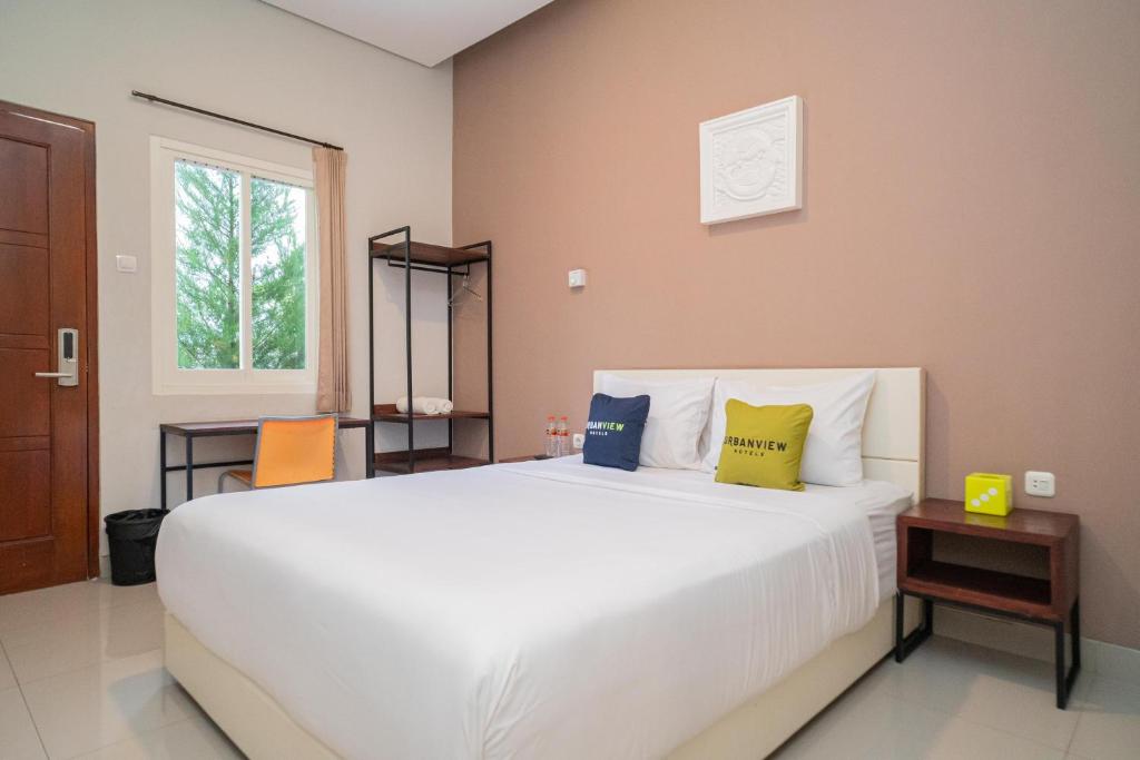 una camera da letto con un grande letto bianco con due cuscini di Urbanview Hotel Bubusini Batu by RedDoorz a Batu