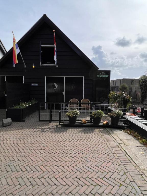 een zwart gebouw met twee vlaggen en enkele planten bij gezellig gastenverblijf in het centrum in Burgh Haamstede