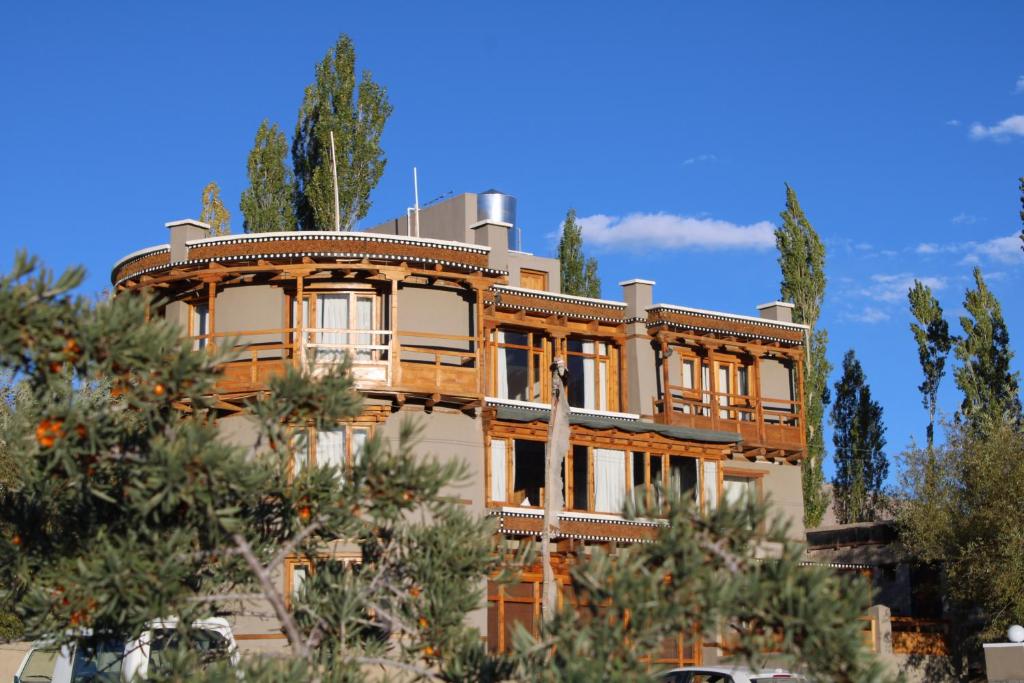 a large building with trees in front of it at Dakpa House Ladakh in Ranbirpura