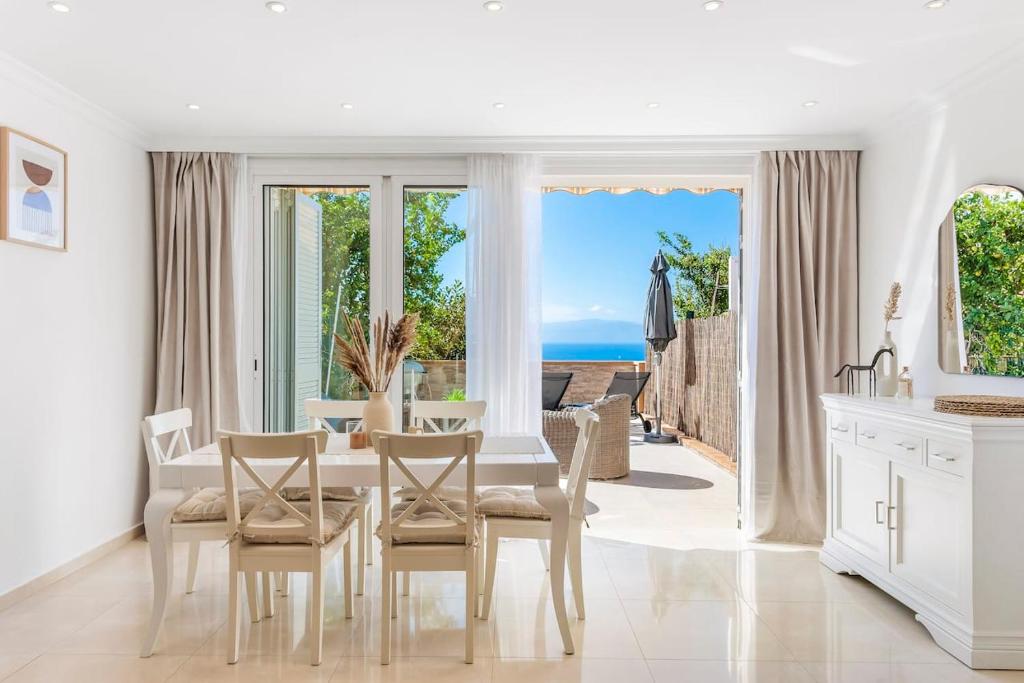 een witte eetkamer met een tafel en uitzicht op de oceaan bij Modern bright and welcoming ocean view apartment in Puerto de Santiago