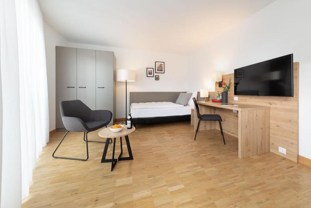 a living room with a bed and a television and a table at Brera Serviced Apartments Stuttgart in Stuttgart