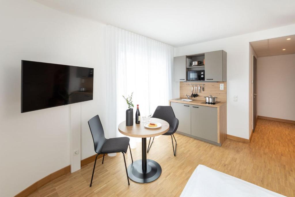 ein Wohnzimmer mit einem Tisch und Stühlen sowie eine Küche in der Unterkunft Brera Serviced Apartments Stuttgart in Stuttgart