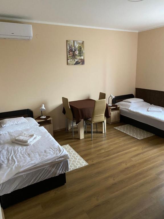 a bedroom with two beds and a table and chairs at Ókerka Vendégház in Csesztreg