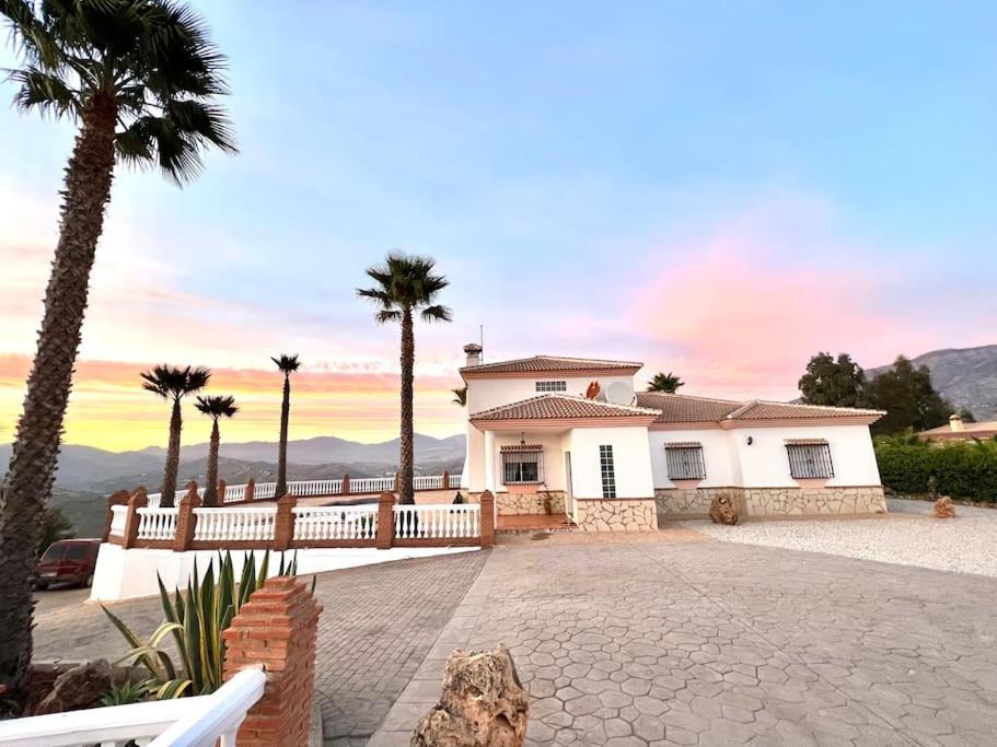 una casa con palme di fronte a un vialetto di CasaBlanca Villa Rural con piscina y barbacoa a Viñuela