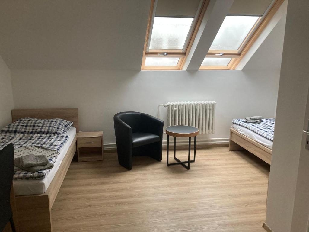 a room with two beds and a chair and a table at Ubytování Na špejcharu, Želevčice in Slaný