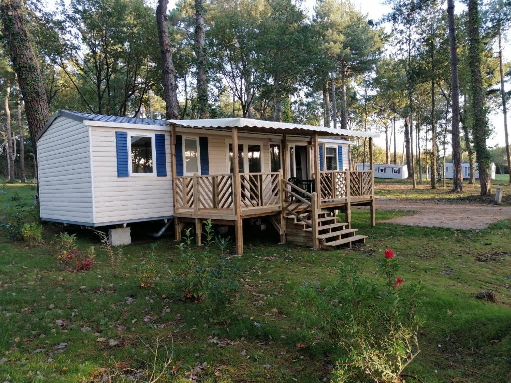 une petite maison dans un champ avec une terrasse couverte dans l'établissement Mobilhome 6/8 personnes Piriac sur Mer, à Piriac-sur-Mer