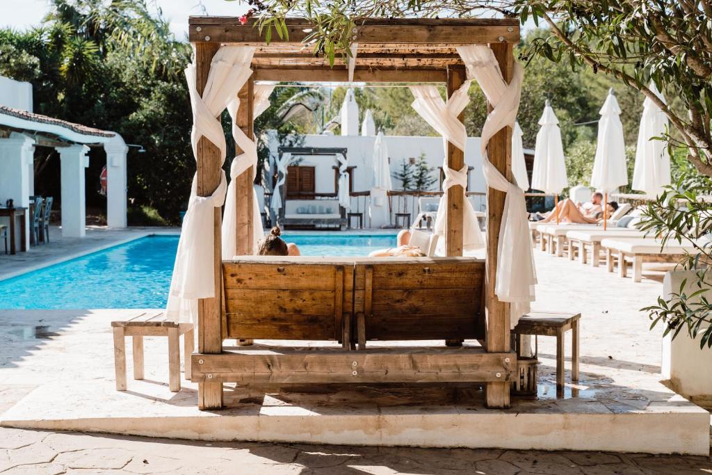 uma cama de madeira em frente a uma piscina em Can Vistabella Boutique Resort em San Antonio