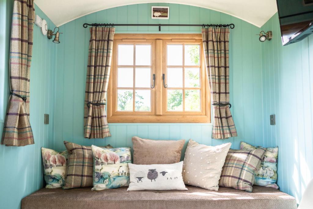 a room with a window and a couch with pillows at Glamping at South Lytchett Manor in Poole