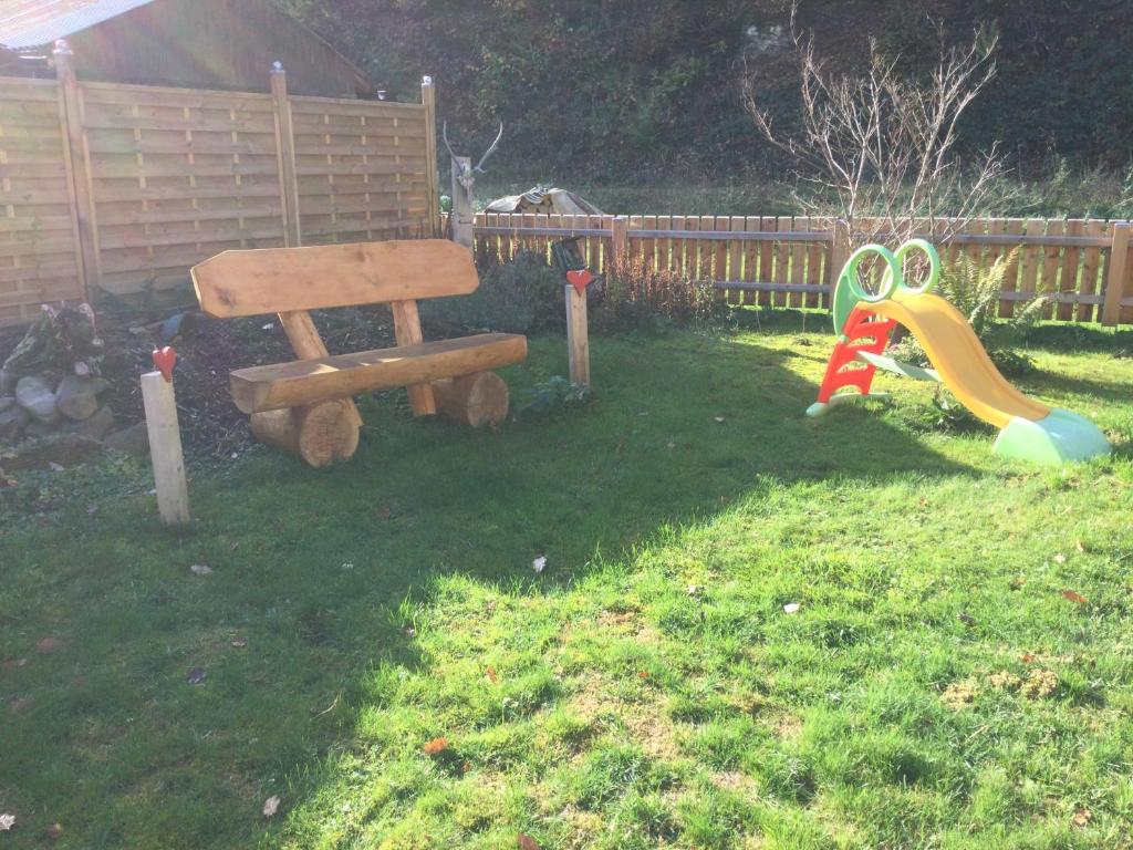 a wooden bench and a slide in a yard at Dani´s Feriendomizil in Wieda